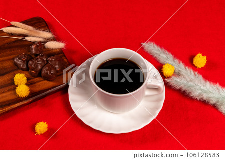 Coffee and chocolate placed on a red carpet with wintery dried flowers 106128583