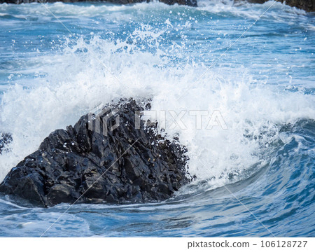 海浪從藍色的大海拍擊著岸邊的岩石,濺起水花。夏季(八月)太平洋海岸。 海浪從藍色的大海拍擊著岸邊的岩石,濺起水花。夏季(八月)太平洋海岸。 106128727
