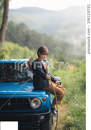 Sitting on the hood of a blue car and looking down while holding a stick Sitting on the hood of a blue car and looking down while holding a stick 106128781