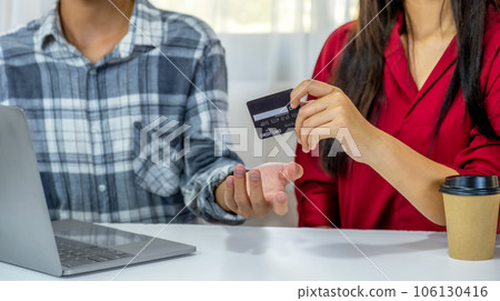 Young couple consumer hand holding mock up credit card, Ready to spend pay online shopping according to discount products via smartphone and laptop from home office 106130416