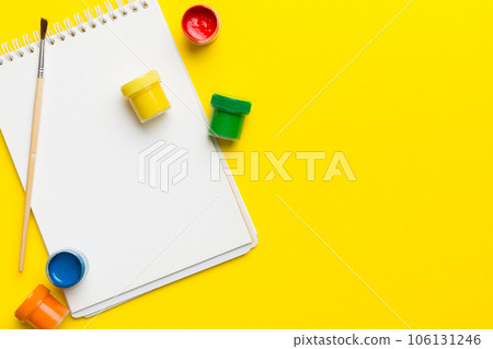 Album pages and paints, pencils, brush on a colored background. Top view with empty space. workplace for creativity. home teaching concept drawing 106131246