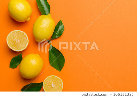 Many fresh ripe lemons with green leaves on colored background, top view, space for text 106131385