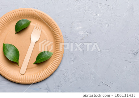 set of empty reusable disposable eco-friendly plates, cups, utensils on light white colored table background. top view. Biodegradable craft dishes. Recycling concept. Close-up set of empty reusable disposable eco-friendly plates, cups, utensils on light white colored table background. top view. Biodegradable craft dishes. Recycling concept. Close-up 106131435