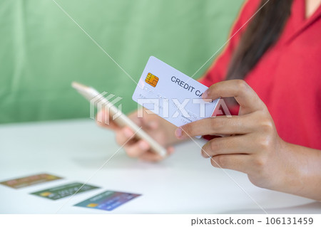 Young consumer woman holding mock up credit card, Ready to spending pay online shopping according to discount products via smartphone and laptop from home Young consumer woman holding mock up credit card, Ready to spending pay online shopping according to discount products via smartphone and laptop from home 106131459