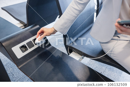 hands of businesswoman charging phone at airport 106132509