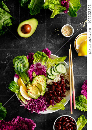 Vegan avocado fresh green salad bowl with red kidney beans, rice, red and chinese napa cabbage, healthy diet food, top view 106132891