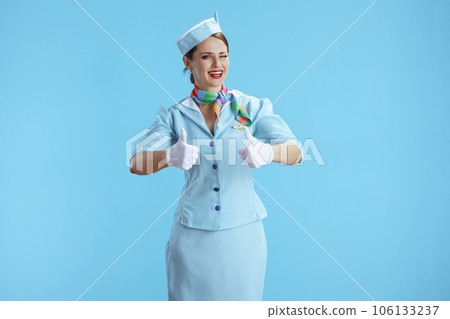 smiling stylish female stewardess on blue showing thumbs up smiling stylish female stewardess on blue showing thumbs up 106133237