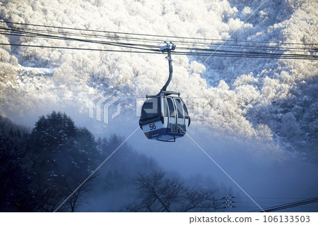 Winter view of gondolas and mountain slopes seen through a break in the mist Winter view of gondolas and mountain slopes seen through a break in the mist 106133503