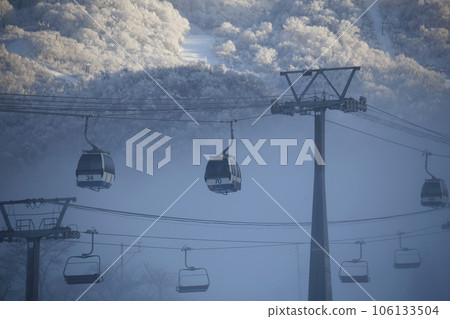 Winter view of gondolas and mountain slopes seen through a break in the mist 106133504