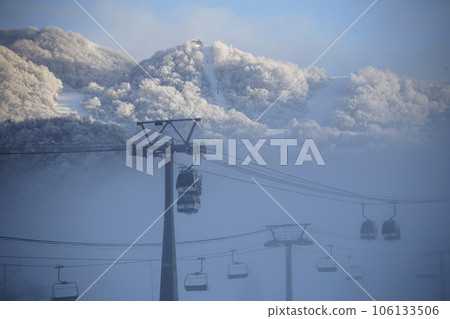 Gondolas and mountain slopes seen through a break in the mist Gondolas and mountain slopes seen through a break in the mist 106133506
