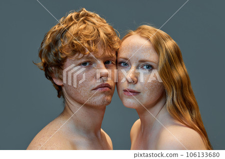 Portrait of beautiful red hair people on grey studio background. Woman and man with freckles and bare shoulders looking at camera. Portrait of beautiful red hair people on grey studio background. Woman and man with freckles and bare shoulders looking at camera. 106133680