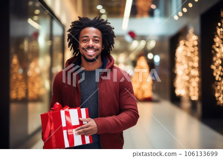 Smiley African American man with a Christmas gift in a mall. Smiley African American man with a Christmas gift in a mall. 106133699
