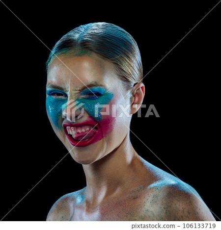 Young beautiful woman with smeared bright makeup under eyes and sparkles on cheeks and bare shoulders. Extraordinary, grimacing face. 106133719