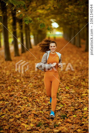 trendy 40 years old woman in fitness clothes in park jogging 106134044