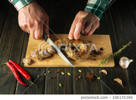 Close-up of the chef's hands with a knife cut meat sausage on a wooden cutting board. Cooking a national meat dish in a restaurant or hotel Close-up of the chef's hands with a knife cut meat sausage on a wooden cutting board. Cooking a national meat dish in a restaurant or hotel 106135266