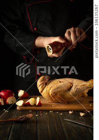 The cook adds pepper to raw duck before roasting. Cooking a national dish or Peking duck in the restaurant kitchen by the hands of a chef The cook adds pepper to raw duck before roasting. Cooking a national dish or Peking duck in the restaurant kitchen by the hands of a chef 106135267