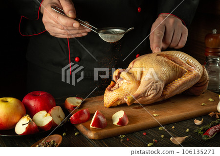 The cook adds paprika to raw duck before roasting in the oven. Cooking a national dish with apples in the restaurant kitchen by the hands of a chef The cook adds paprika to raw duck before roasting in the oven. Cooking a national dish with apples in the restaurant kitchen by the hands of a chef 106135271
