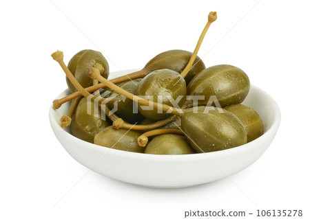 Capers in ceramic bowl isolated on white background. Pickled or canned capers. Capers in ceramic bowl isolated on white background. Pickled or canned capers. 106135278