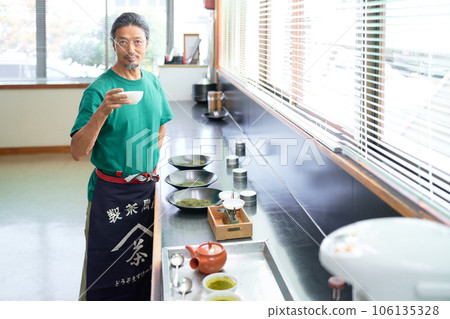 A veteran tea master holding a teacup in his hand and directing his gaze A veteran tea master holding a teacup in his hand and directing his gaze 106135328