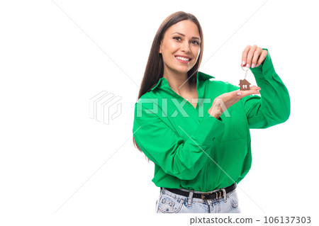 young smiling european brunette woman with brown eyes in a green blouse holding her house keychain 106137303
