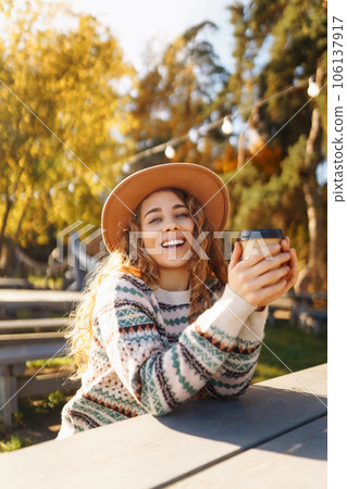 Fall concept woman drinking coffee on bench against backdrop of lake. Enjoying, solitude with nature Fall concept woman drinking coffee on bench against backdrop of lake. Enjoying, solitude with nature 106137917