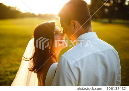 Lovely wedding couple at sunset. Bride, groom in wedding attire with bouquet of flowers. Romantic. 106138482