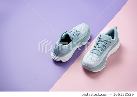 New light blue green female modern running shoe on pink purple and white geometrical background. Stylish monochrome shoes for active people that incorporate new health technology. Top view 106138529