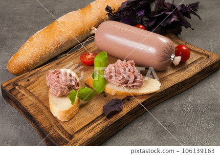pate on a baguette on a wooden board decorated with basil and cherries pate on a baguette on a wooden board decorated with basil and cherries 106139163