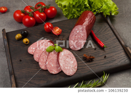 smoked sausage servelat or salami on a dark wooden background smoked sausage servelat or salami on a dark wooden background 106139230