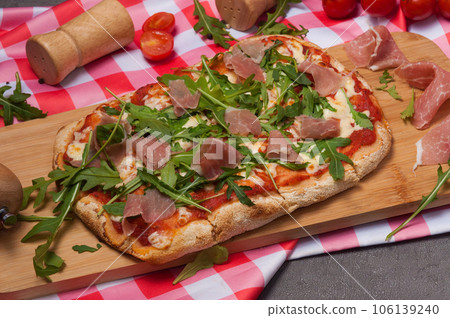 roman pizza with jamon and arugula on a wooden board 106139240