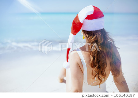 Seen from behind woman in swimsuit sitting at beach Seen from behind woman in swimsuit sitting at beach 106140197