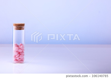 Pink pills in a glass bottle on a blue background. Health care, medical pills and nutritional supplements Pink pills in a glass bottle on a blue background. Health care, medical pills and nutritional supplements 106140785