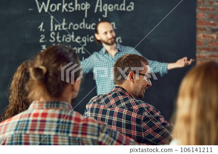 Male expert speaker giving talk at business meeting. Rear view of business people having workshop, discussing answers and questions of coach. 106141211