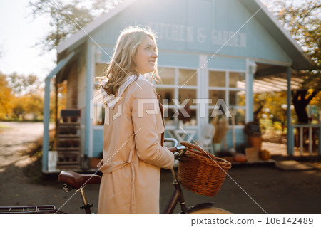 Beautiful woman with a bike on the background of a blue house in the fall. 106142489
