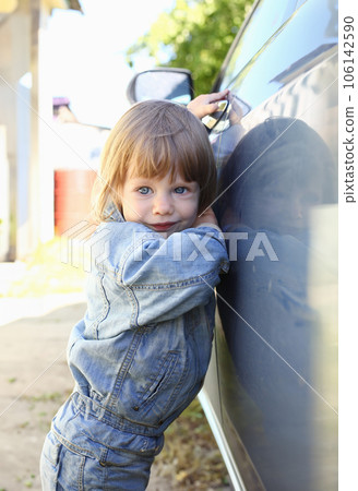 Little fashion child holds the car handle in a jeans jacket Little fashion child holds the car handle in a jeans jacket 106142590