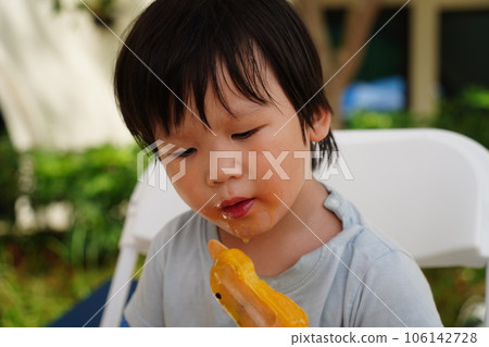 A child is eating a popsicle. A child is eating a popsicle. 106142728
