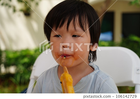 A child is eating a popsicle. 106142729
