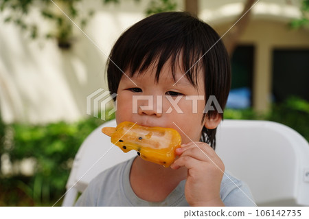 A child is eating a popsicle. 106142735