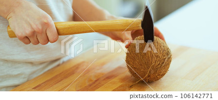 Closeup on woman opening coconut using hammer Closeup on woman opening coconut using hammer 106142771