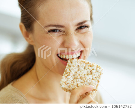 Happy young woman eating crisp bread Happy young woman eating crisp bread 106142782