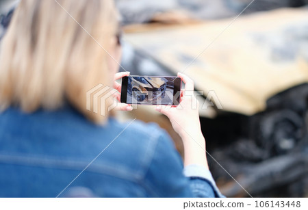 Female insurance agent takes photo of burnt-out car on phone 106143448