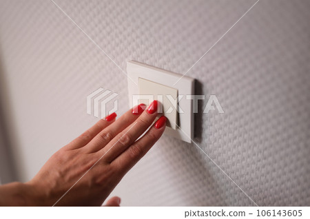 Closeup of woman hand is turned off on light switch at home Closeup of woman hand is turned off on light switch at home 106143605