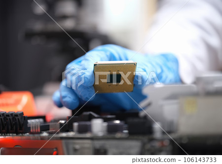 Technician puts processor on computer motherboard socket Technician puts processor on computer motherboard socket 106143733