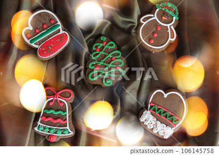 Banner for Christmas and New Year gingerbread. Christmas trees, toys, snowmen, garlands on a background of brown silk fabric. Bright bokeh. Banner for Christmas and New Year gingerbread. Christmas trees, toys, snowmen, garlands on a background of brown silk fabric. Bright bokeh. 106145758