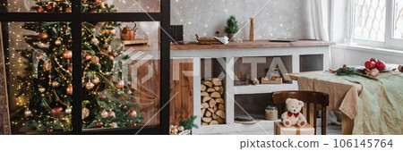 Home New Year's interior. Christmas tree with gifts, decorated with garlands in the kitchen. Cozy atmosphere of a home holiday, loft design of the room, Scandinavian style. Home New Year's interior. Christmas tree with gifts, decorated with garlands in the kitchen. Cozy atmosphere of a home holiday, loft design of the room, Scandinavian style. 106145764