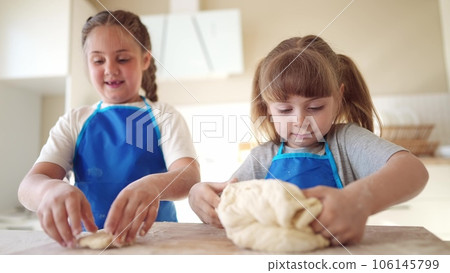 children making dough in the kitchen. two little girls cook in the kitchen knead dough and flour fun indoors. happy family kid dream concept. children play cooking dough together at home 106145799