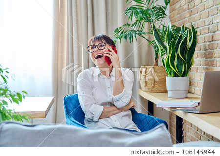Happy middle aged woman talking on mobile phone, at home Happy middle aged woman talking on mobile phone, at home 106145944