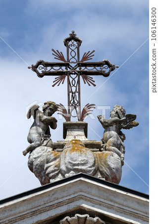 Angels kneeling under the cross, statue on facade of the Mantua Cathedral dedicated to Saint Peter, Mantua, Italy 106146300