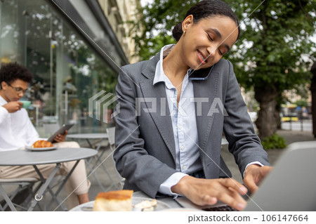 Pretty business woman talking on the phone and working on laptop Pretty business woman talking on the phone and working on laptop 106147664
