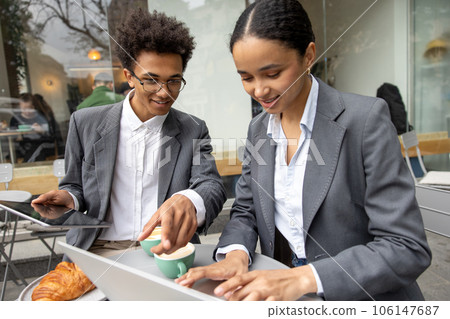 Business partners discussing something and working on laptop together 106147687